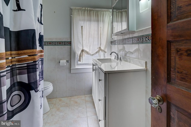 bathroom with tile walls, vanity, tile patterned flooring, and toilet