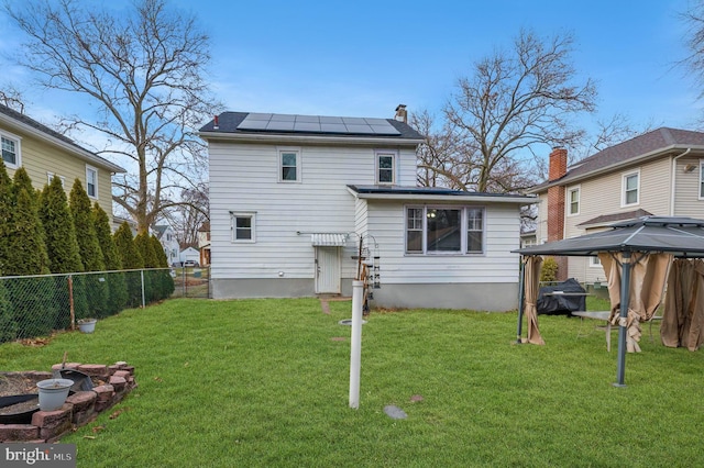 rear view of property with a gazebo, a lawn, and solar panels