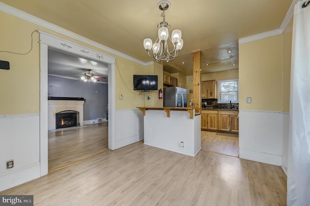 kitchen featuring stainless steel fridge with ice dispenser, pendant lighting, a breakfast bar area, kitchen peninsula, and a brick fireplace