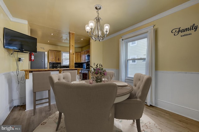 dining room featuring an inviting chandelier, crown molding, and light wood-type flooring