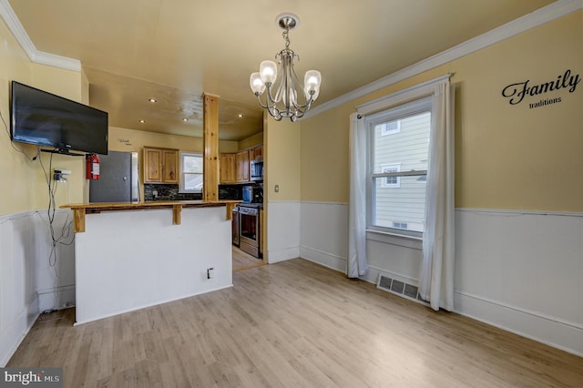 kitchen featuring a kitchen bar, a notable chandelier, kitchen peninsula, stainless steel appliances, and light wood-type flooring