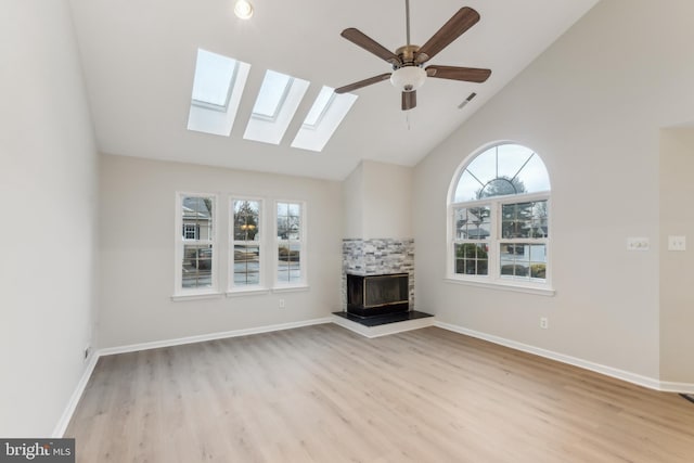 unfurnished living room with a fireplace, light wood finished floors, visible vents, vaulted ceiling, and baseboards