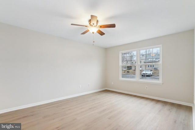 unfurnished room with a ceiling fan, light wood-style flooring, and baseboards