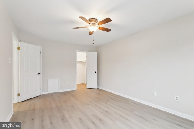 unfurnished bedroom with a spacious closet, light wood finished floors, a closet, and baseboards