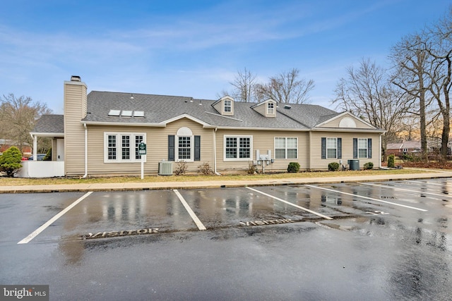 view of property featuring uncovered parking and central AC unit