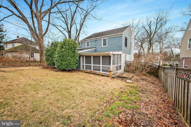 rear view of house with a sunroom and a lawn