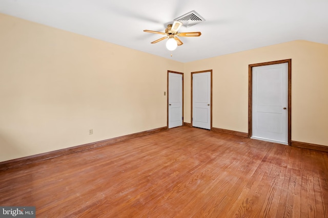 unfurnished bedroom with ceiling fan, vaulted ceiling, and light wood-type flooring