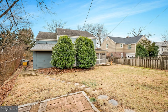 back of property featuring a sunroom and a lawn