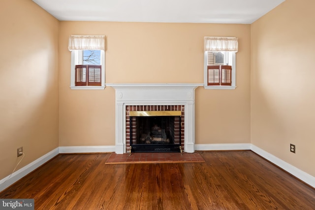 unfurnished living room with a brick fireplace and dark hardwood / wood-style floors