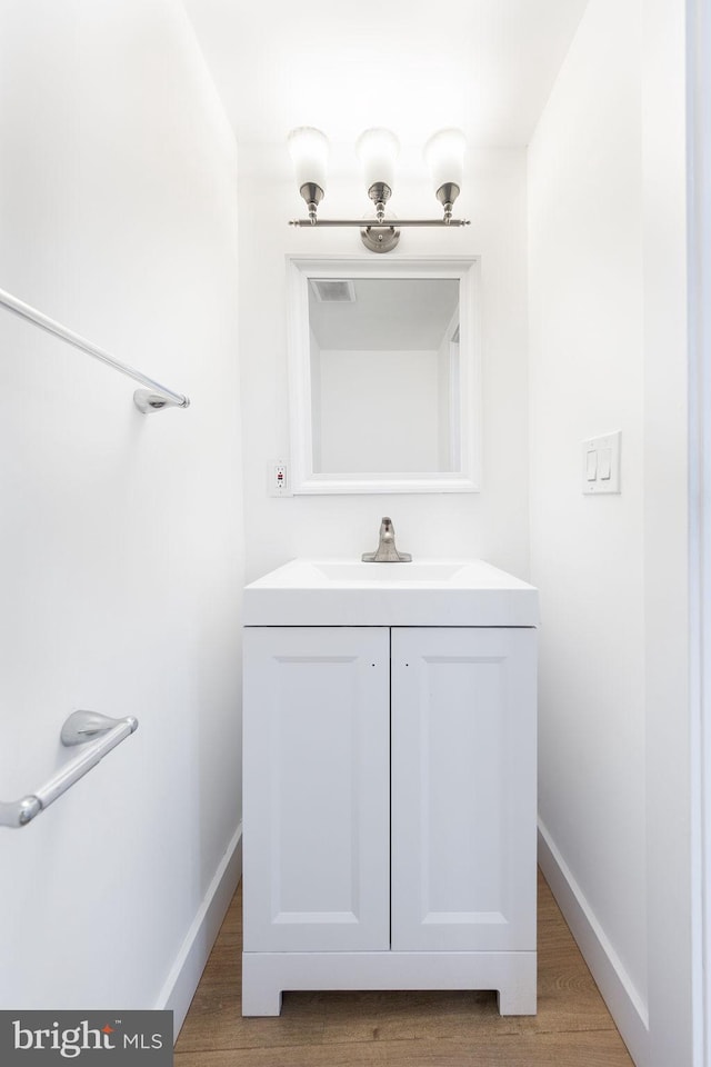 bathroom with vanity, wood finished floors, visible vents, and baseboards