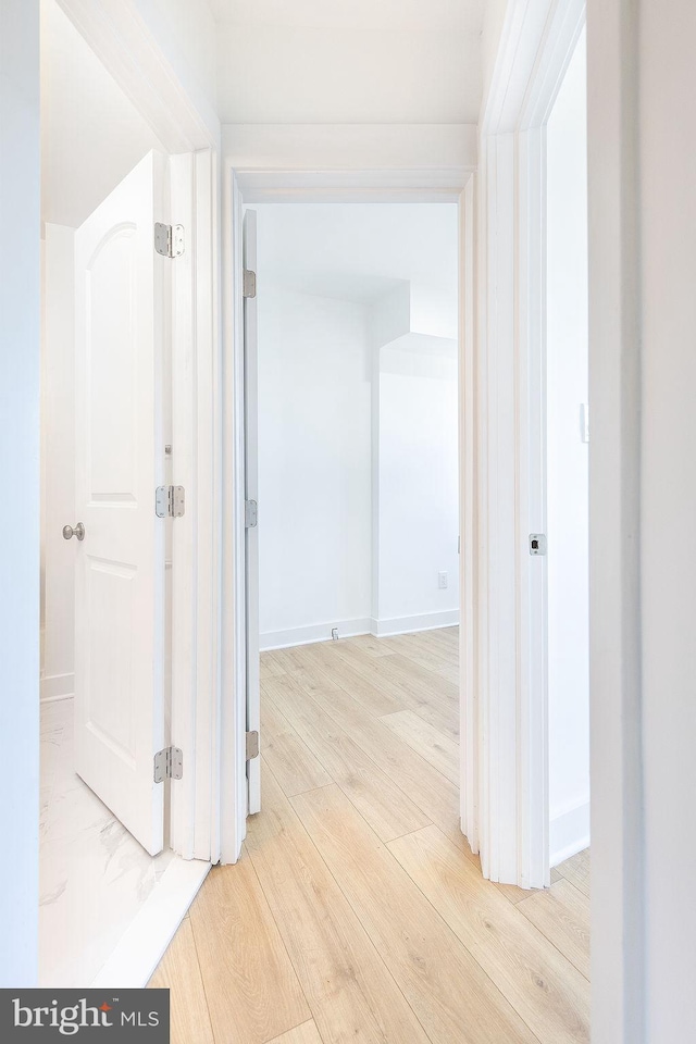 hall featuring light wood-style floors and baseboards