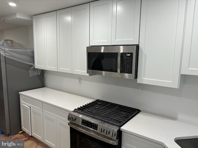 kitchen featuring light stone countertops, appliances with stainless steel finishes, white cabinets, and recessed lighting