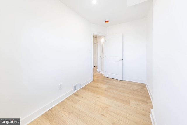 empty room with light wood-style floors, baseboards, and visible vents