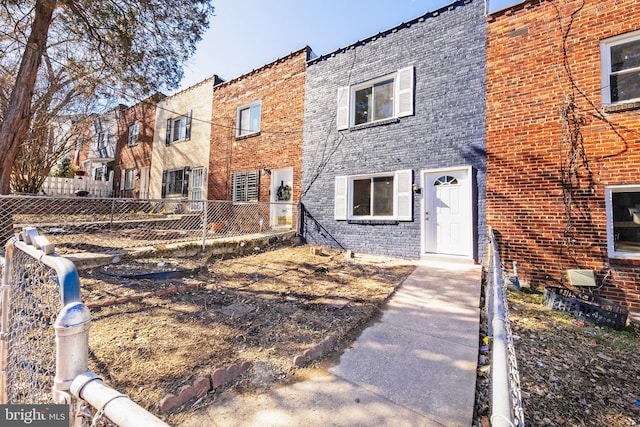 view of property with brick siding and fence