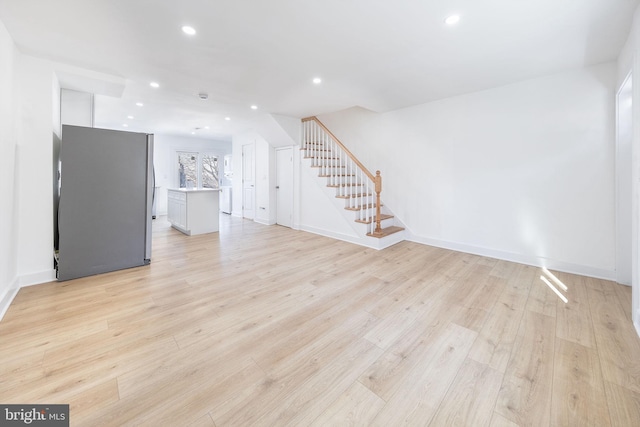 unfurnished living room with light wood finished floors, baseboards, stairway, and recessed lighting