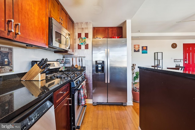 kitchen with dark stone countertops, light hardwood / wood-style floors, and appliances with stainless steel finishes