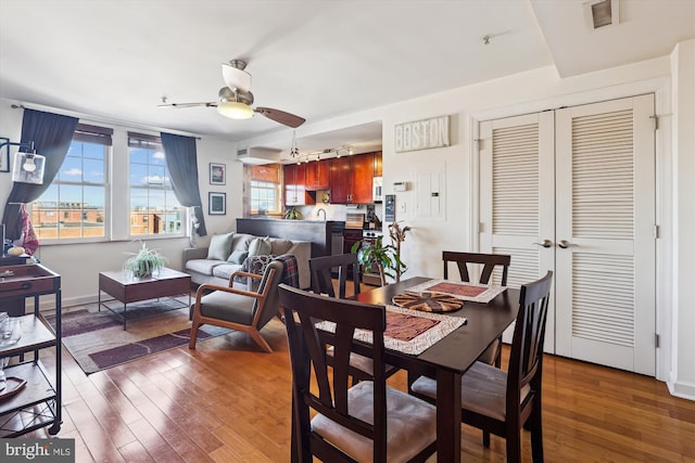 dining room with ceiling fan, rail lighting, and dark hardwood / wood-style flooring