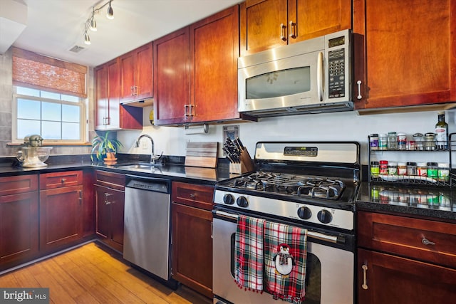 kitchen with rail lighting, appliances with stainless steel finishes, sink, and light hardwood / wood-style flooring