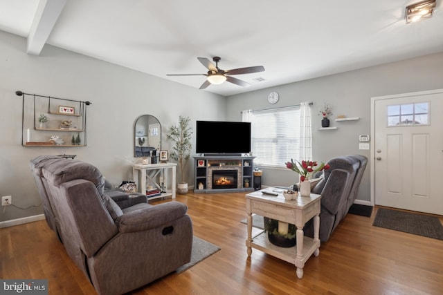 living room with ceiling fan, hardwood / wood-style floors, a fireplace, and beam ceiling