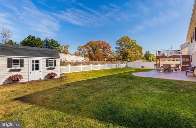 view of yard featuring a deck, a patio area, and a storage unit