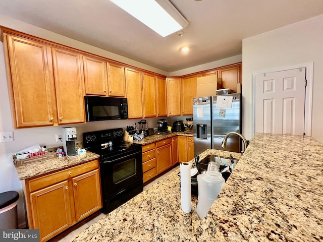 kitchen with light stone countertops, black appliances, and sink