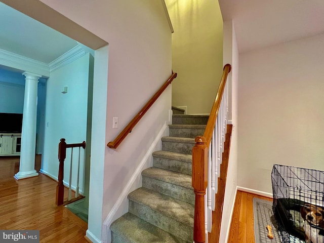 stairs featuring decorative columns, ornamental molding, and hardwood / wood-style flooring