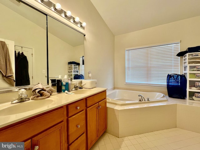 bathroom with tile patterned flooring, vaulted ceiling, a relaxing tiled tub, and vanity