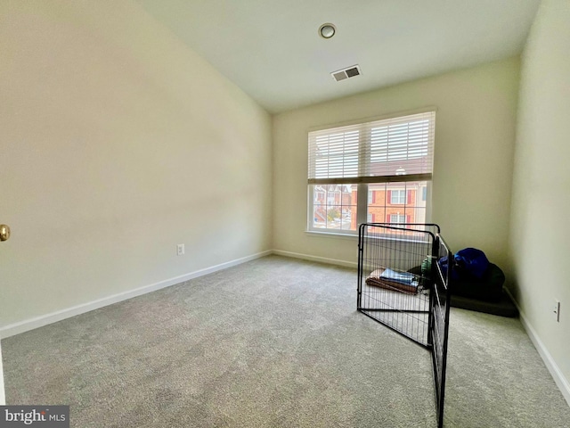 carpeted spare room featuring vaulted ceiling