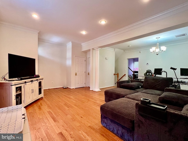 living room with crown molding, light hardwood / wood-style flooring, a chandelier, and ornate columns