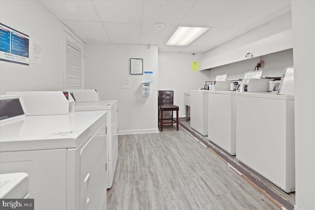 laundry room with washing machine and clothes dryer and light wood-type flooring