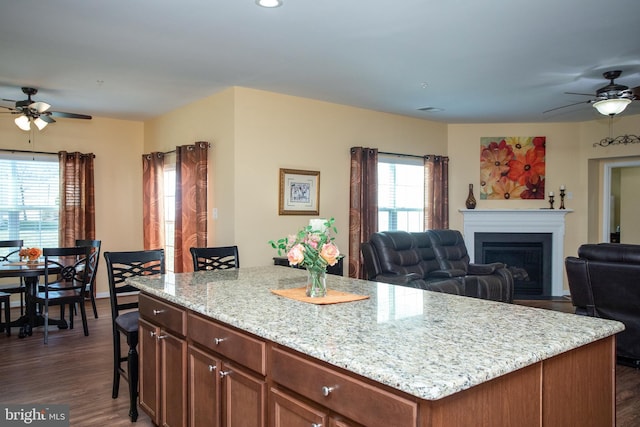 kitchen featuring ceiling fan, a kitchen island, a breakfast bar area, and dark hardwood / wood-style flooring