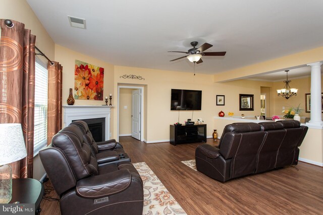 living room featuring dark hardwood / wood-style flooring, ceiling fan with notable chandelier, and ornate columns