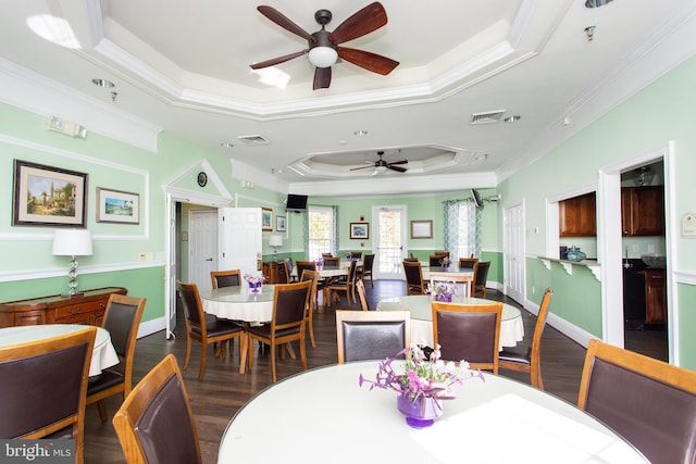 dining area with crown molding, a tray ceiling, and dark hardwood / wood-style floors