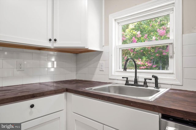 kitchen with butcher block counters, sink, white cabinetry, and decorative backsplash