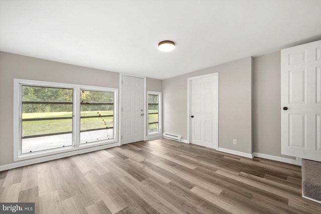 spare room featuring hardwood / wood-style flooring, a baseboard radiator, and plenty of natural light