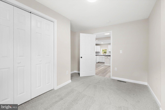 unfurnished bedroom featuring light carpet and a closet