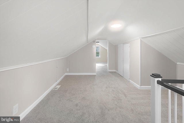 additional living space featuring light colored carpet and vaulted ceiling