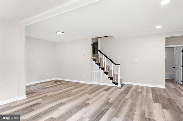 spare room featuring beam ceiling and light hardwood / wood-style flooring