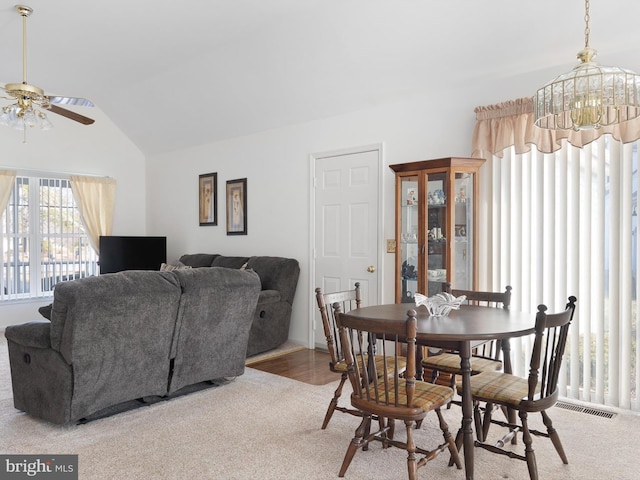 dining room with lofted ceiling and ceiling fan with notable chandelier