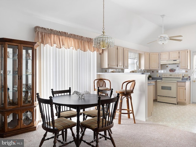 dining space featuring lofted ceiling, ceiling fan with notable chandelier, and light carpet