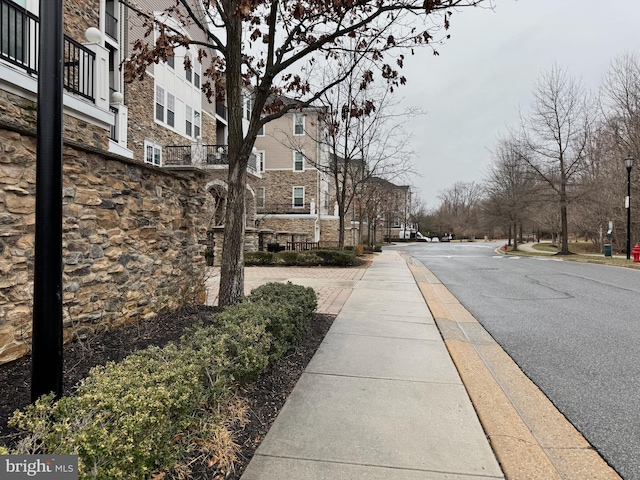 view of street featuring a residential view, curbs, street lighting, and sidewalks