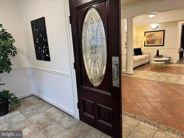 foyer entrance featuring tile patterned floors, baseboards, ornamental molding, and ornate columns