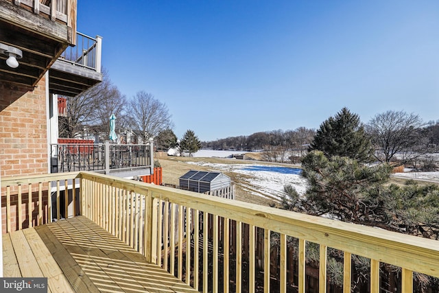 snow covered deck featuring a storage shed