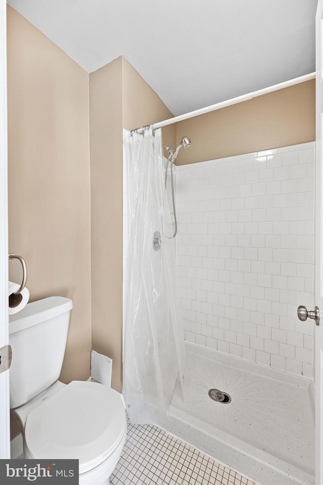 bathroom featuring tile patterned flooring, toilet, and walk in shower