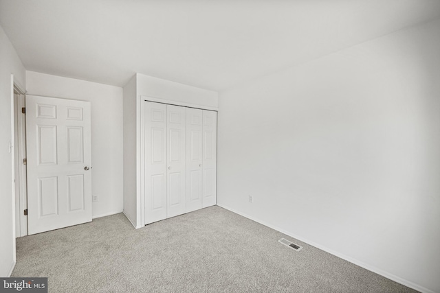 unfurnished bedroom with light colored carpet and a closet