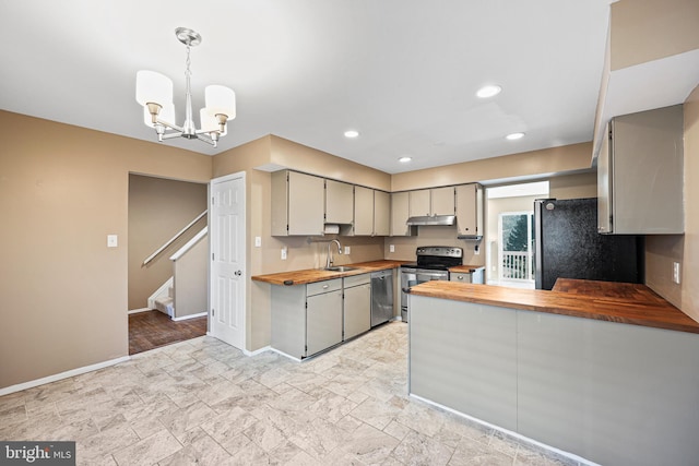 kitchen featuring appliances with stainless steel finishes, sink, wooden counters, a chandelier, and hanging light fixtures