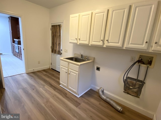 clothes washing area featuring wood-type flooring, sink, cabinets, hookup for a washing machine, and electric dryer hookup