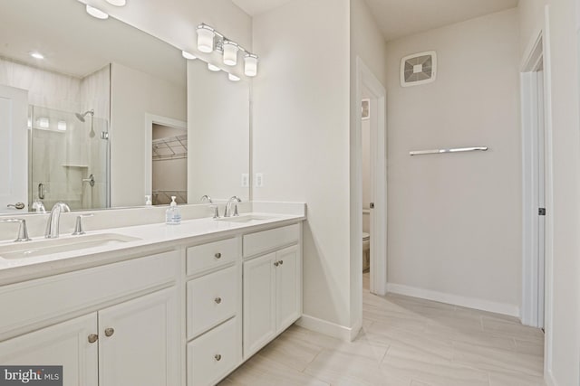 bathroom featuring toilet, a shower stall, double vanity, and a sink