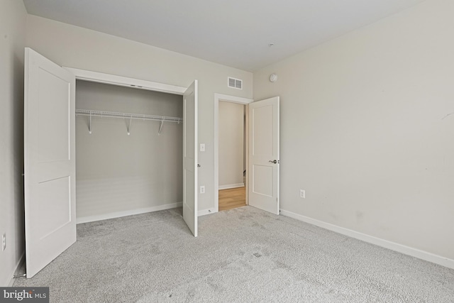 unfurnished bedroom featuring carpet floors, a closet, visible vents, and baseboards