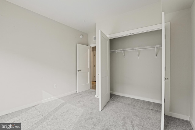 unfurnished bedroom featuring light carpet, baseboards, and a closet